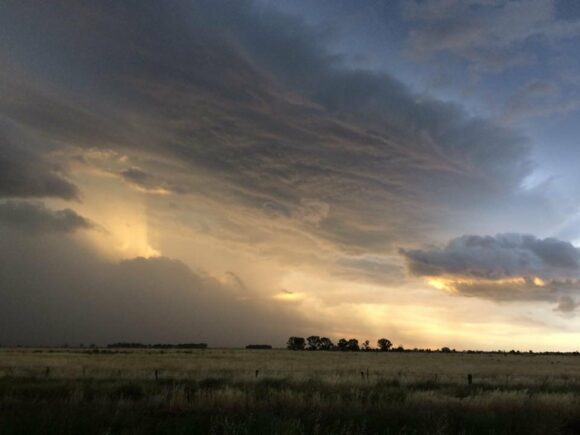 Sun setting through behind the storm with sunlight illuminating the cloud bases and features